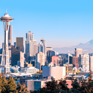 A scenic daytime view of downtown Seattle featuring the iconic Space Needle, modern skyscrapers, and distant mountain ranges, highlighting the urban setting ideal for finding a dispensary near Seattle.