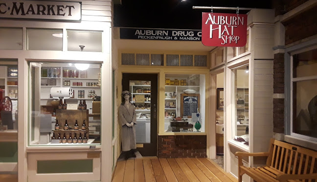 Historic storefront display featuring Auburn Drug Company and Auburn Hat Shop with vintage decor and mannequin